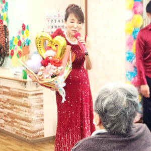 深紅のドレスでプレゼントを手にする美空えり子さん